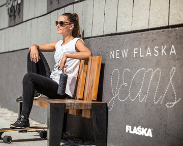 Eine Frau sitzt auf einer Bank mit einer Flaska Jeans Flasche