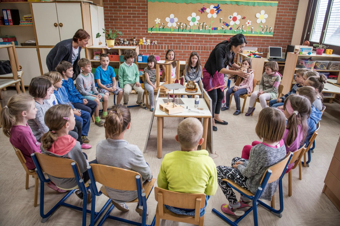 akiko stein erklärt in einem kreis sitzenden kindern das emoto peace project