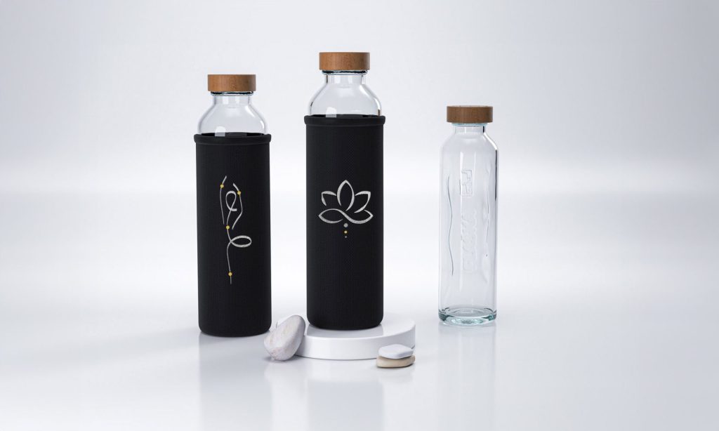 drei glas trinkflaschen mit schwarzen hüllen und holzdeckeln zwei haben minimalistische designs