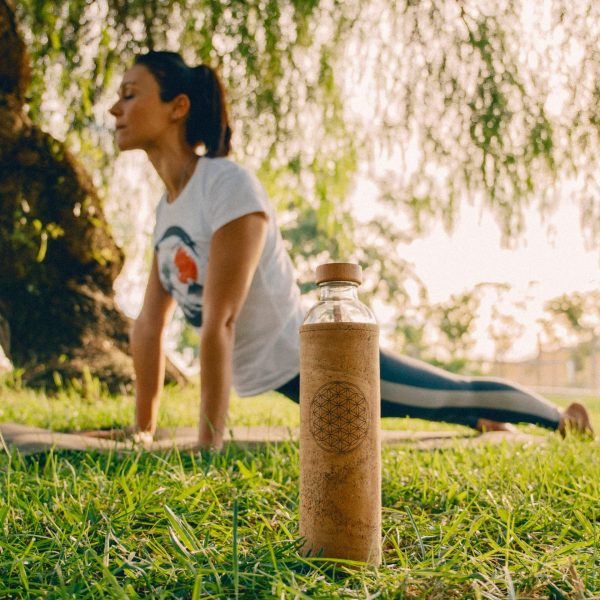 frau macht yoga im freienmit kork wasserflasche mit blume des lebens design